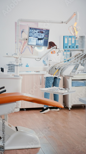 Vertical video  Stomatologist using chair with tools for dental care in dentistry cabinet. Dentist preparing teethcare equipment for examination in office designed for dentistry checkup
