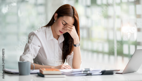 Young Asian businesswoman working on laptop computer, stressed has a headache and thinks hard from work at the office.