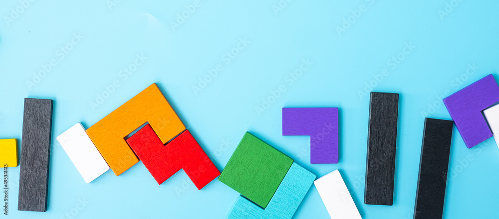 colorful wood puzzle pieces on blue background, geometric shape block with copy space. Concepts of logical thinking, Conundrum, solutions, rational, strategy, world logic day and Education