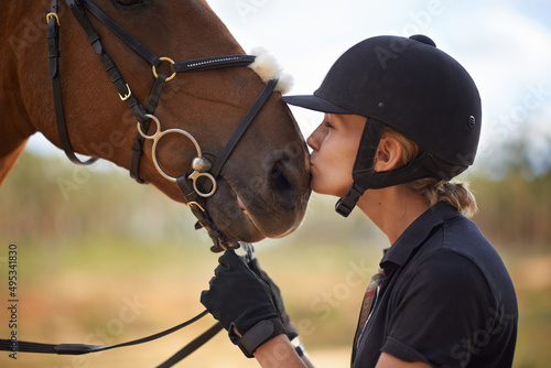 There is a bond between horse and rider. A young female rider being affectionate with her chestnut horse. © Tasneem H/peopleimages.com