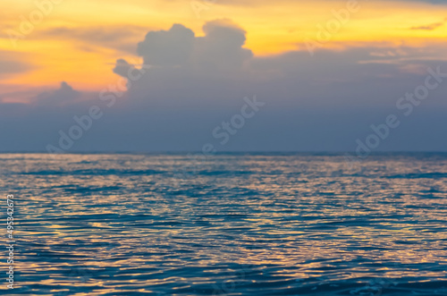 Partial focus of the sea that have sun light reflection with yellow sky and cloud when sunset.