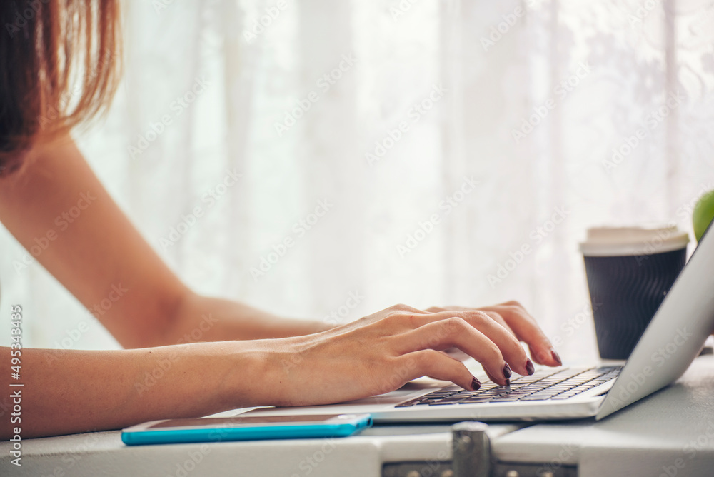 Fototapeta premium Blogger Woman hands typing laptop keyboard. Close up women hands using laptop social network person. Freelance girl work from home via internet call conference sitting at home office morning time