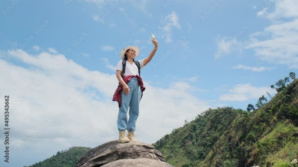 Hipster woman in hat relaxing in nature on vacation and taking selfie with smartphone on mountain background.