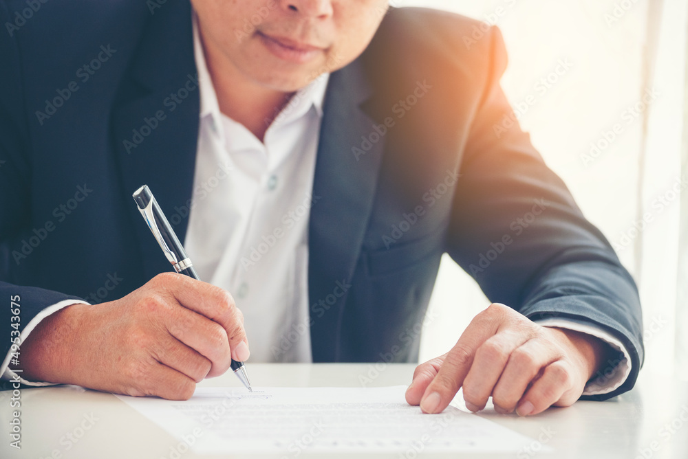 Obraz premium Businessman hand using pen signing on new contract to starting projects in conference room. Close up business manager man hands sign contract legal document in meeting room. Business agreement concept