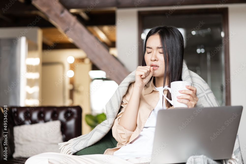 Young asian woman feeling sick, coughing and drinking hot tea. Girl