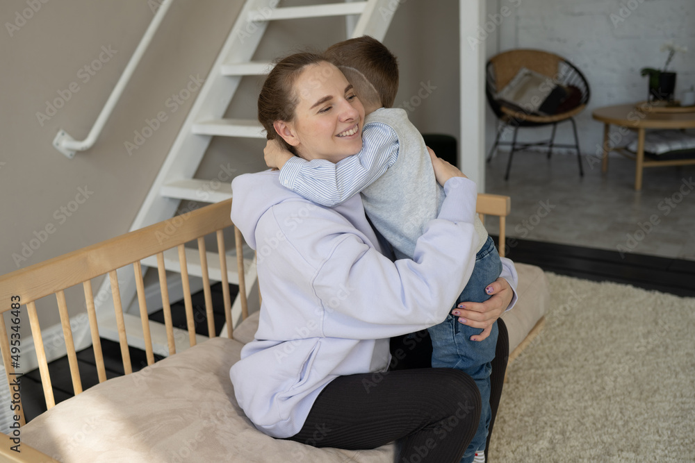 Happy mom and son hug, spend time at home together, look at each other. A mother on maternity leave plays with her son. Mother's Day. Preschool age. Home family cute photo.