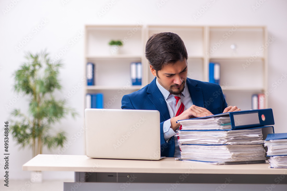Young male employee unhappy with excessive work in the office Young male employee unhappy with excessive work in the office