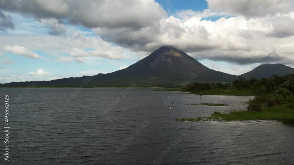 Huge tropical volcano peak and lake among clouds. Panning wide aerial Huge tropical volcano peak and lake among clouds. Panning wide aerial