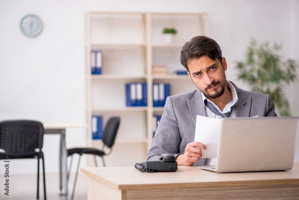 Young male employee and too much work in the office Young male employee and too much work in the office