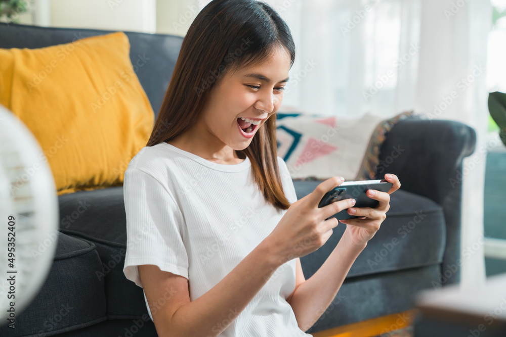Excited Young Asian woman playing an online game on a smartphone. Excited Young Asian woman playing an online game on a smartphone.