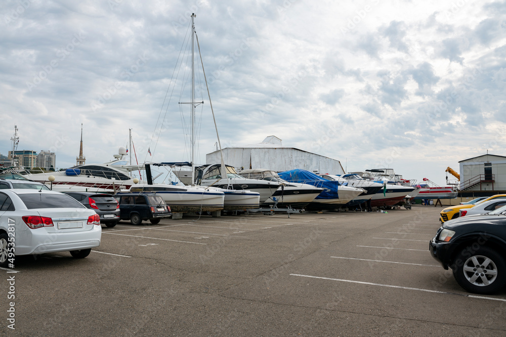 Fototapeta premium Parking for cars, yachts and boats against a cloudy sky.