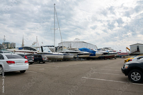 Parking for cars, yachts and boats against a cloudy sky.