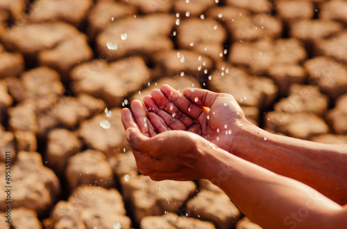 hands washing with water pouring from a tap on dry ground.