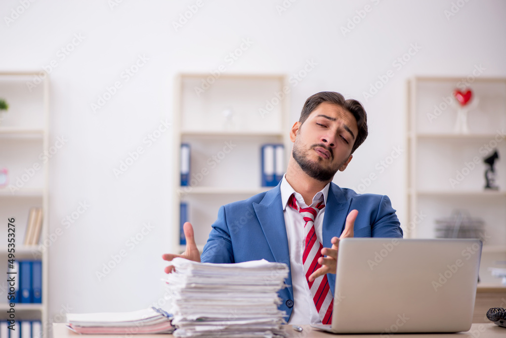 Young male employee and too much work in the office Young male employee and too much work in the office