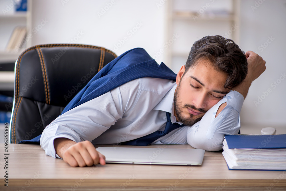 Young male employee extremely tired in the office Young male employee extremely tired in the office