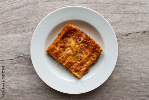 Italian meat Lasagne in a white dish on wooden background. Portion of traditional Lasagna on a plate. Top view