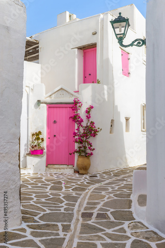 Fototapeta Naklejka Na Ścianę i Meble -  Traditional Cycladitic alley with narrow street, whitewashed houses and a blooming bougainvillea in Marpissa Paros island, Greece.