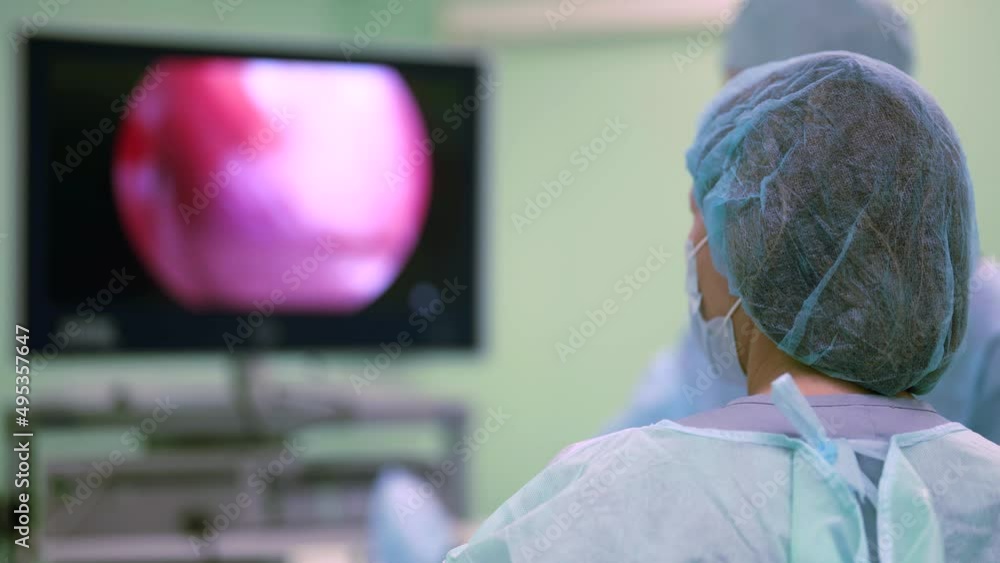Surgeon Using Monitor Endoscopic surgery on the monitor. A female surgeon performs an ...