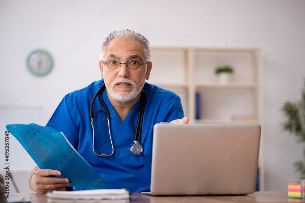 Old male doctor working in the clinic Old male doctor working in the clinic
