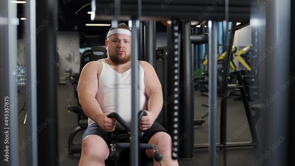 Fat burning, overweight funny man lifting blocks on rowing machine, training on block device and gym equipment, motivation. Fat burning, overweight funny man lifting blocks on rowing machine, training on block device and gym equipment, motivation.