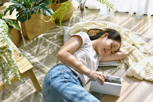 Woman chilling and reading book in living room, Artificial plant, Fiddle leaf fig tree, Indoor tropical natural houseplant for home interior and air purification.