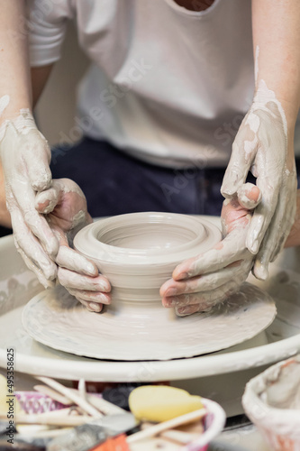 A woman with red hair, white paper and jeans, in a pottery workshop, working behind a potter's wheel photo