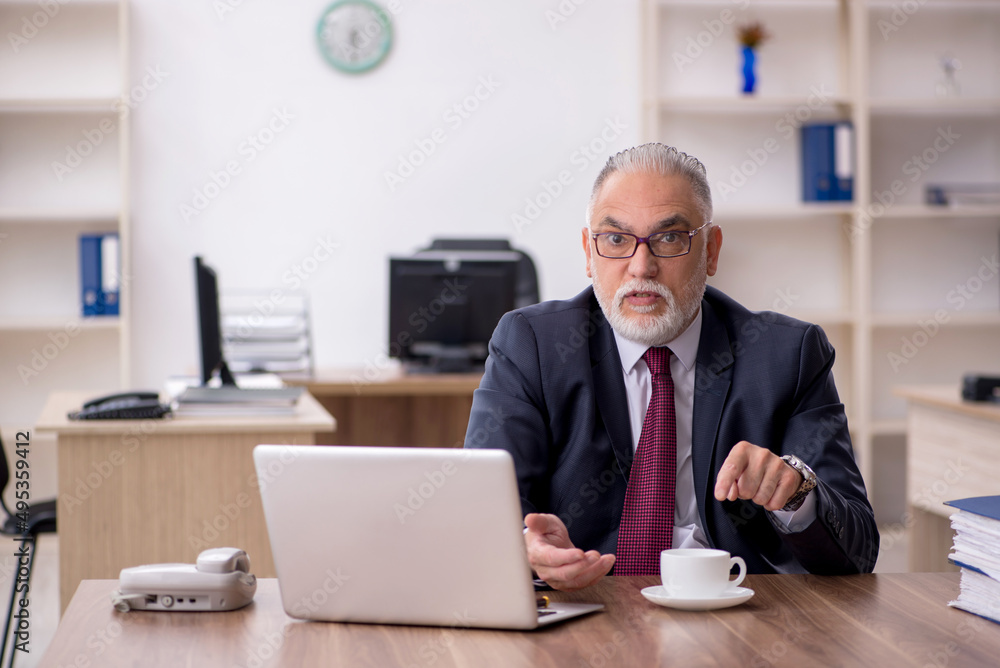 Old male employee drinking coffee during break Old male employee drinking coffee during break