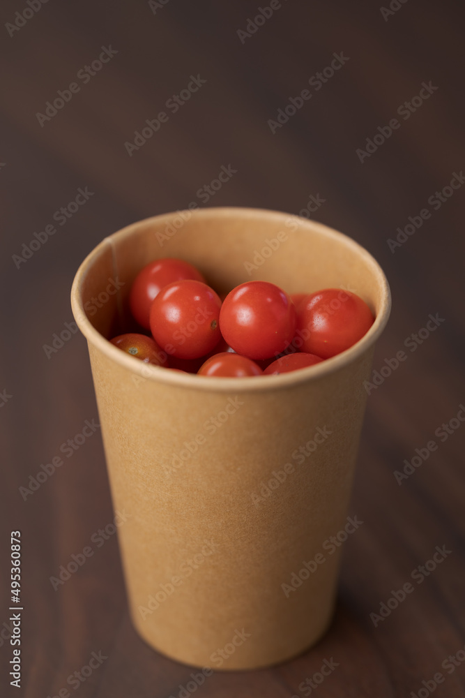 Cherry tomatoes in papaer cup container on wood table Cherry tomatoes in papaer cup container on wood table