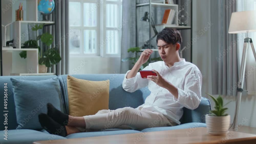 Full Body Of Asian Man Being Upset Losing Game On Smartphone While Lying On Sofa In The Living Room
Full Body Of Asian Man Being Upset Losing Game On Smartphone While Lying On Sofa In The Living Room