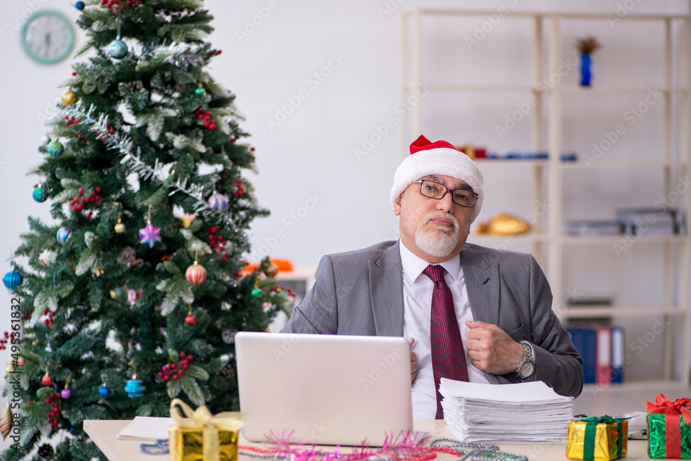 Aged male employee celebrating Christmas at workplace Aged male employee celebrating Christmas at workplace