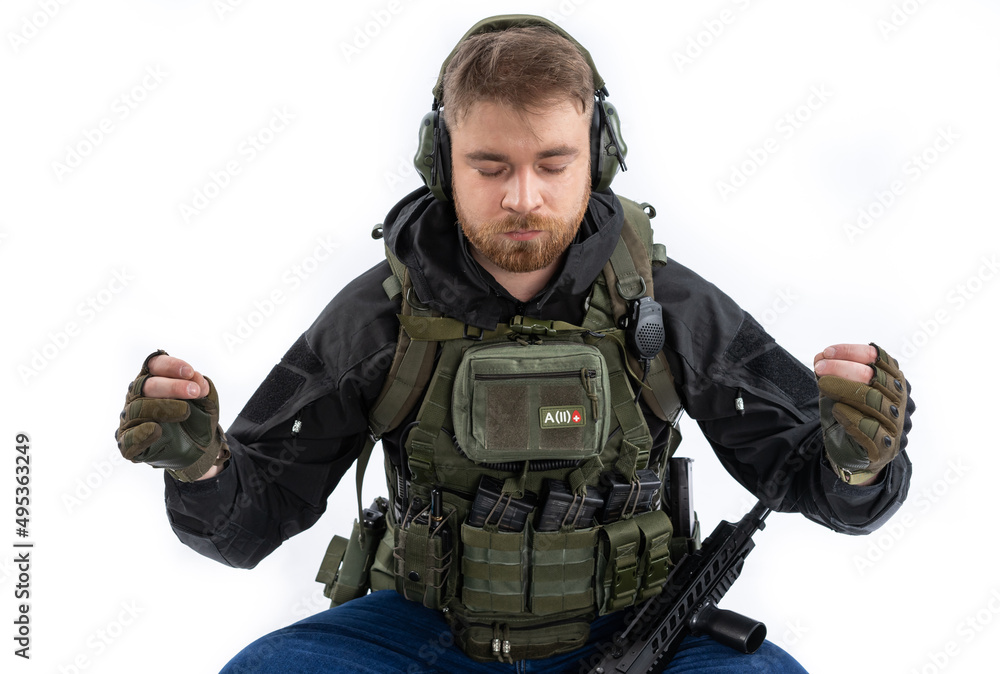 a soldier in full gear is tired, resting at a halt. man in headphones, body armor, backpack and belt. White background. a soldier in full gear is tired, resting at a halt. man in headphones, body armor, backpack and belt. White background.