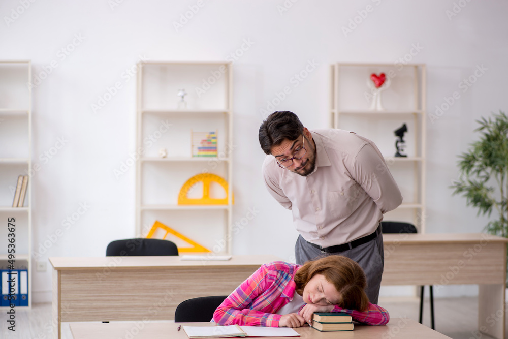 Young male teacher and redhead girl in the classroom Young male teacher and redhead girl in the classroom