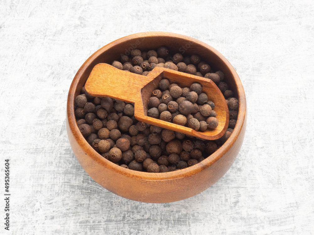 Spice Allspice in wooden bowl and scoop on white concrete background. Macro. Healthy eating concept Spice Allspice in wooden bowl and scoop on white concrete background. Macro. Healthy eating concept