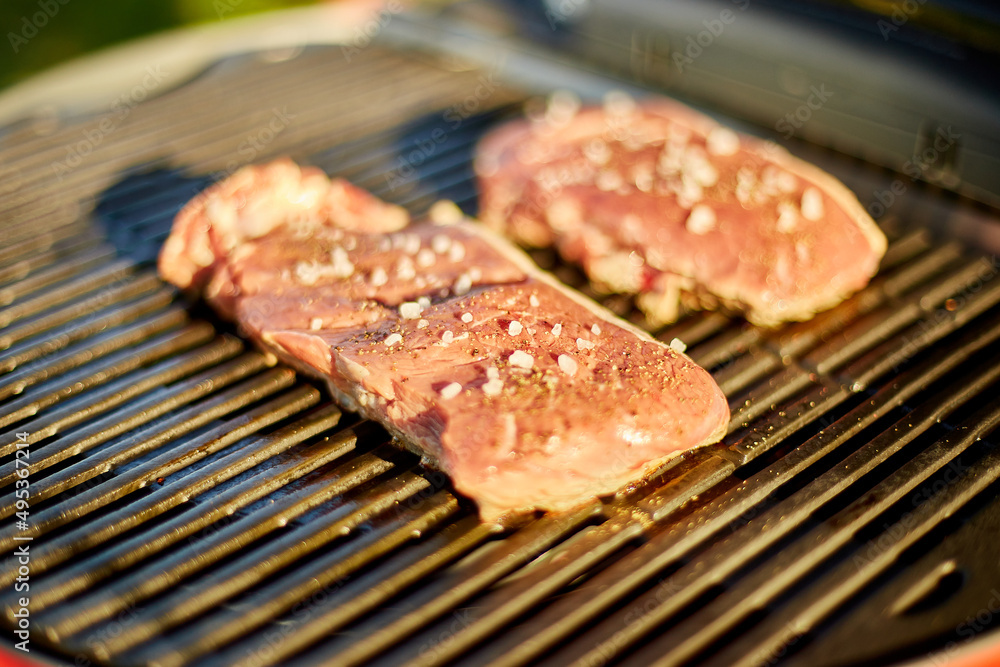 Roasted meat on the gas grill on barbecue grill outdoor in the backyard, grilled steak meat