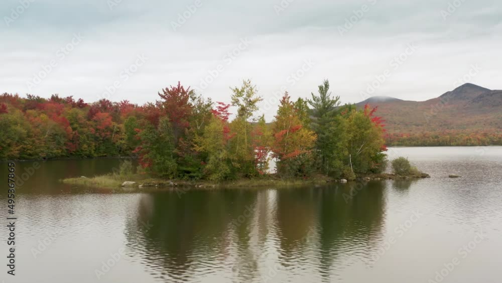 Cinematic aerial island in mountain lake, Vermont peak season foliage background Cinematic aerial island in mountain lake, Vermont peak season foliage background