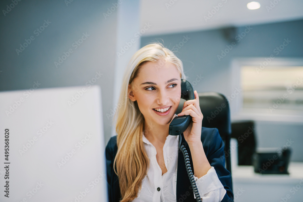 A happy secretary talking on the phone from modern office. - obrazy, fototapety, plakaty 