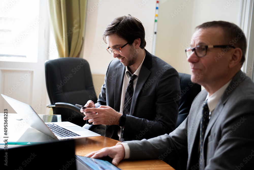 Young businessman using phone during roundtable business meeting Young businessman using phone during roundtable business meeting