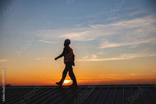 A construction worker walking on the roof of the building. photo