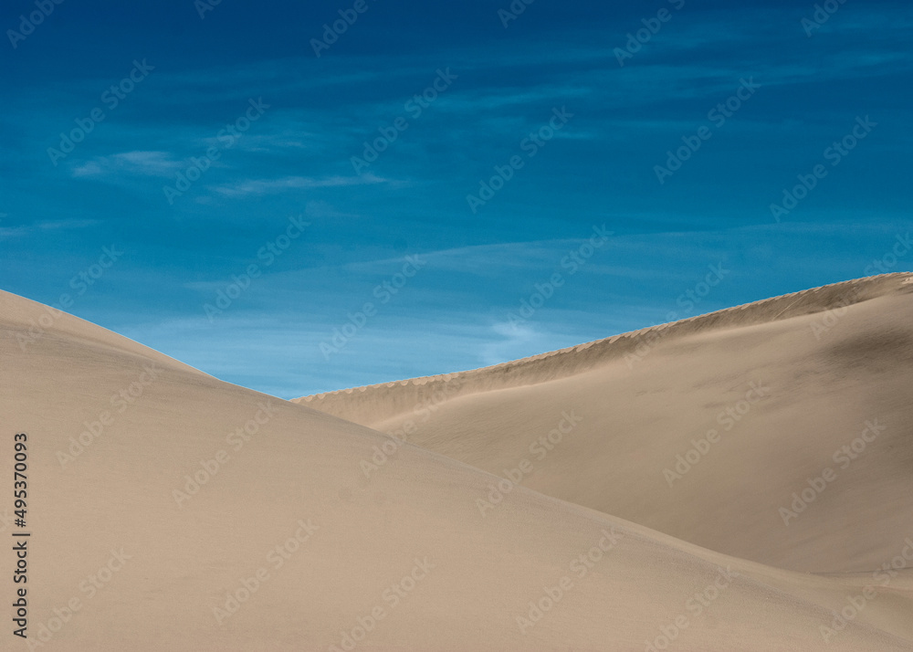 Desert landscape. Sand dunes under the blue sky. Traces of wind on the surface of the sand dune.