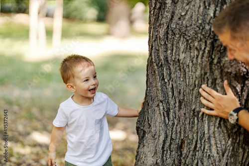A son playing seek and hide with his father in woods. photo