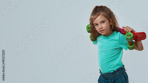 Preschooler girl with skateboard looking at camera