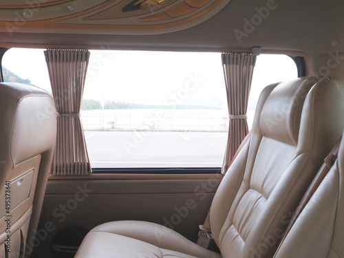 Empty brown leather seats in van with outdoor view. © pkanchana