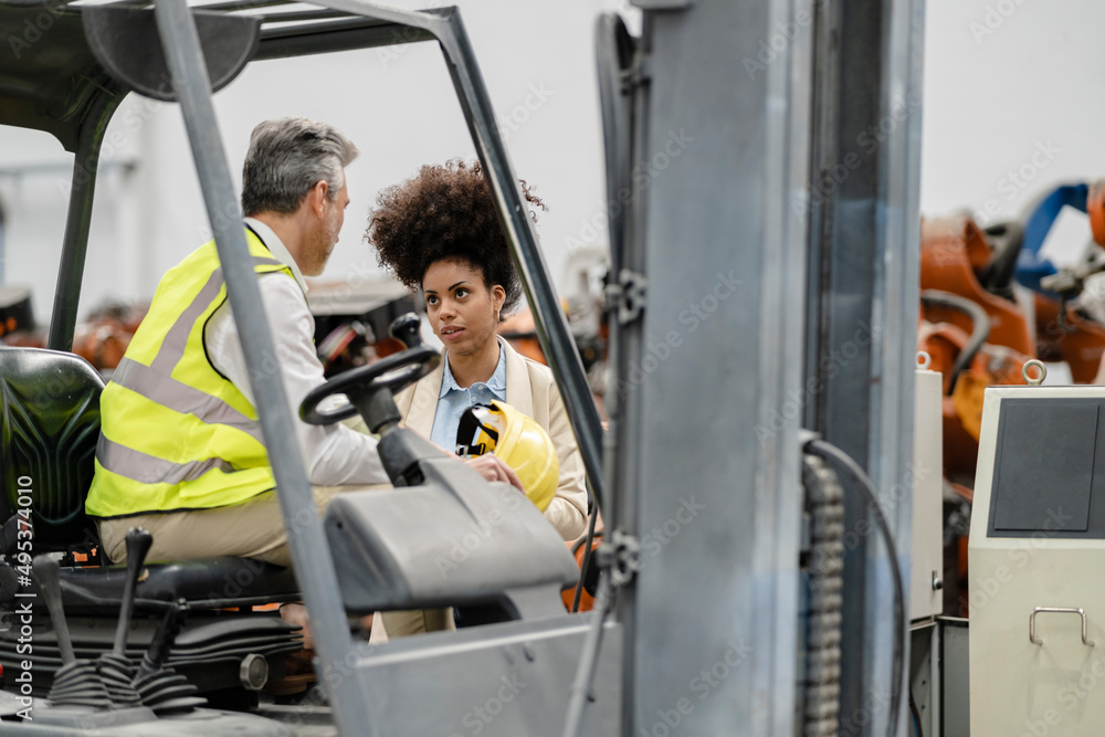 Businesswoman discussing with engineer in factory Businesswoman discussing with engineer in factory
