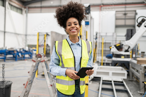 Happy technician holding tablet PC standing in factory photo
