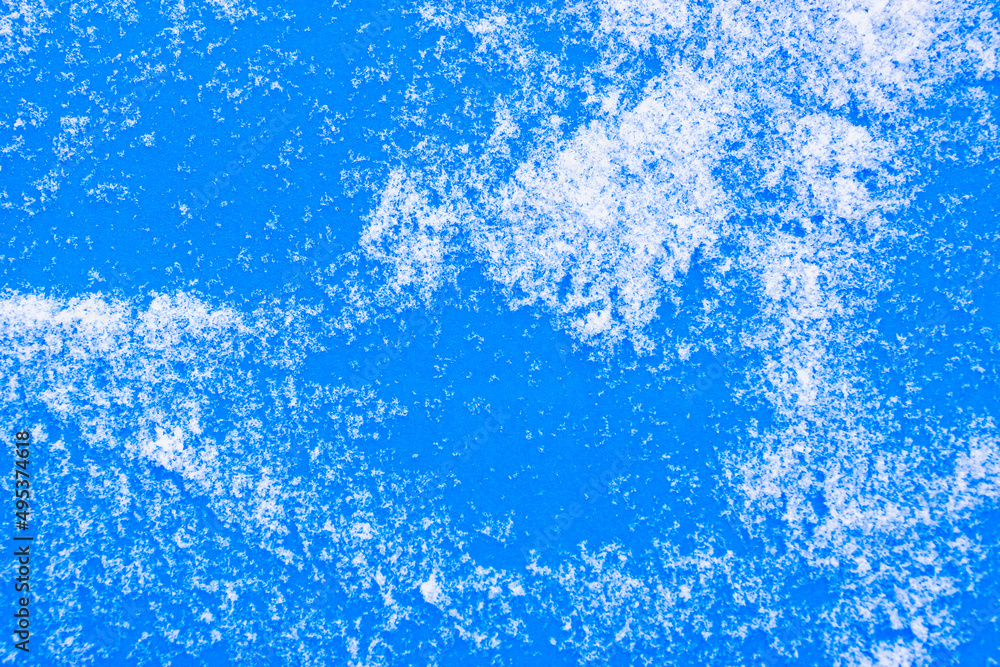Blue background with white snow grains (copy space).