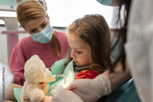 Dentist making cute little girl comfortable for examining at dental clinic photo