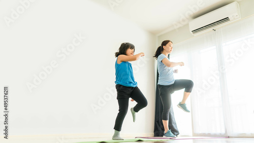 Fototapeta Naklejka Na Ścianę i Meble -  Video streaming.home fitness workout class live streaming online.Asian mother and child girl strength training cardio aerobic dance exercises at home.Activity mom and kid together.determination child.
