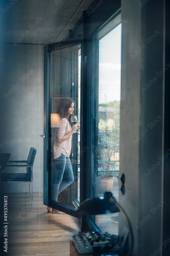 Woman with wineglass standing by window at home Woman with wineglass standing by window at home