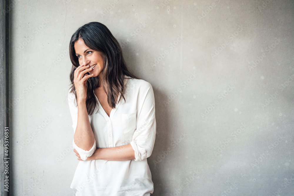 Smiling beautiful woman standing in front of wall Smiling beautiful woman standing in front of wall