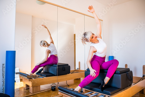 Woman is exercising on pilates reformer bed at home. photo
